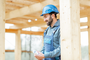 e overalls and hard hat on the construction site. Building wooden frame house concept