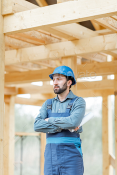 e overalls and hard hat on the construction site. Building wooden frame house concept