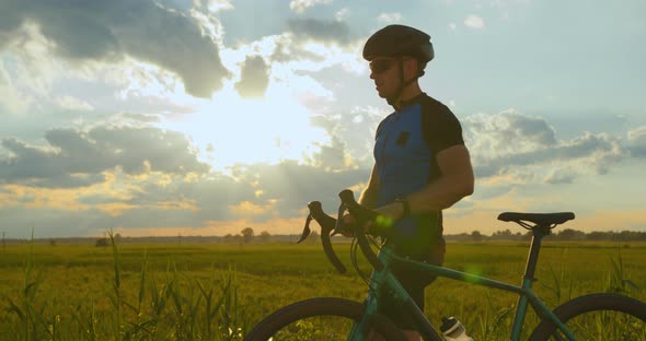 A Sportsman is Walking Along the Road with a Bicycle