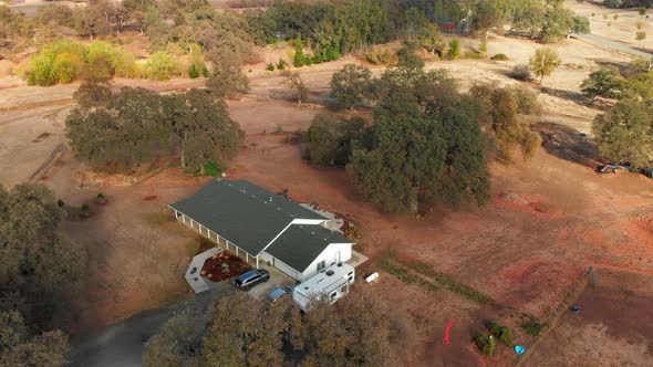 Aerial Drone shot that pans down to rural a farm home in oak trees