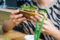 Girl holding Vietnamese baguette Banh Mi with fresh vegetables and grilled pork - PhotoDune Item for Sale