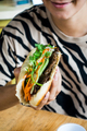 Girl eating Vietnamese baguette Banh Mi with fresh vegetables and grilled pork - PhotoDune Item for Sale