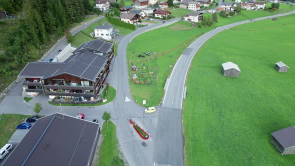 Road in Austrian Alp Valley Between Green Fields and Wooden Houses Aerial View