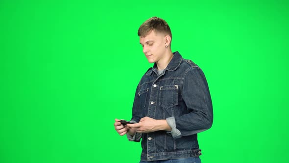 Smiling Man Goes and Takes a Selfie with Smartphone on Green Screen at Studio.