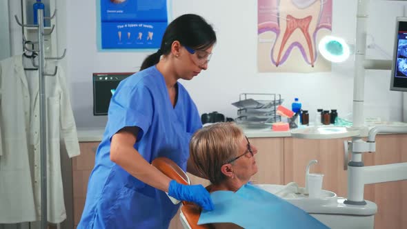 Nurse Preparing Patient Arranging Dental Bib