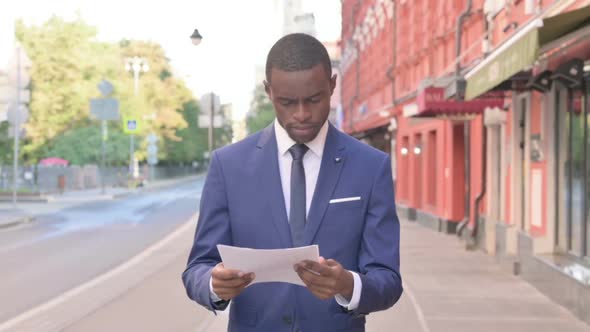 Walking African Businessman Reading Documents