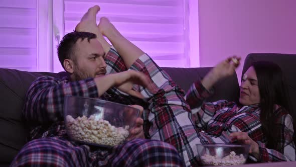 Married Couple is Watching TV and Eating Popcorn