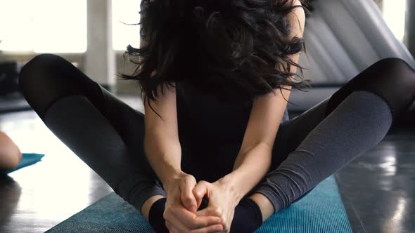 Young Caucasian Woman Stretching and Smiling at Camera on the Gym Floor