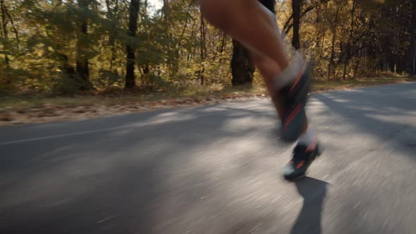 Running Man In Forest At Sunset. Runner Man Fit Athlete Legs Jogging On Trail Ready To Triathlon.