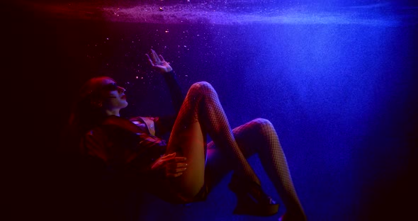 a Girl Is Wearing Platform Shoes and Dark Glasses. She Floats in a Stream of Bubbles Under the Water