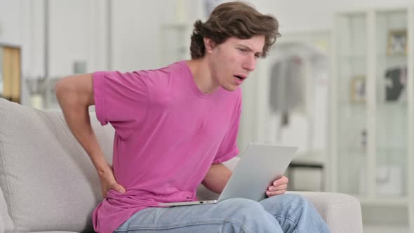 Young Casual Man with Back Pain Using Laptop at Home