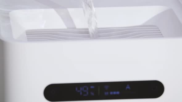 Close Up Man Pouring Water Into White Humidifier Tank