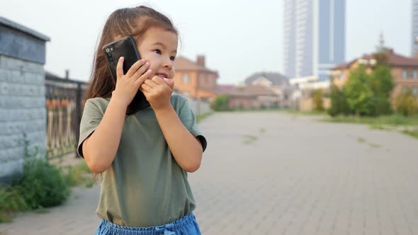 Little Korean Girl Talks on Phone on Empty City Embankment