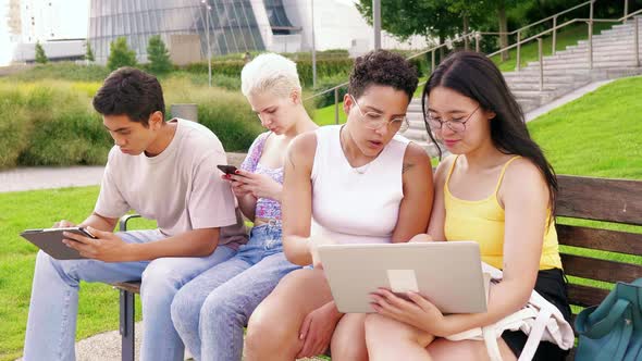 Small group young multiethnic friends outdoor using devices