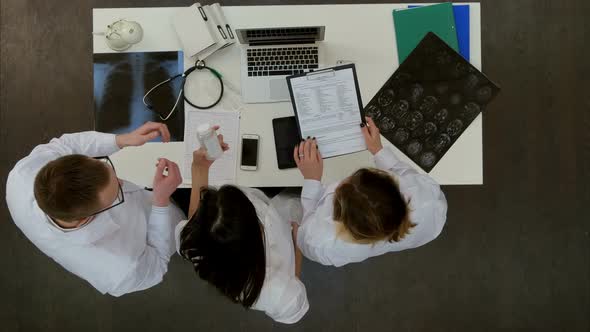 Medical Team Discussing What Pills To Prescribe Using Laptop