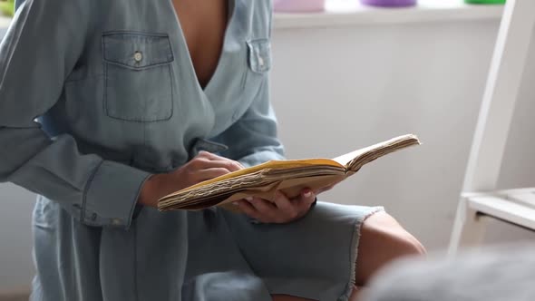 Young blonde girl reading a book at home
