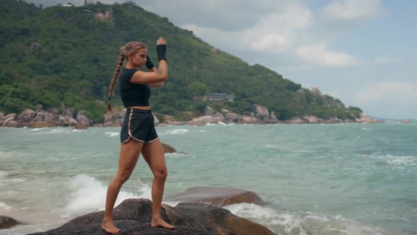 Healthy Female Athlete Stands on a Big Stone By the Sea and Practices the Correct Kick in the