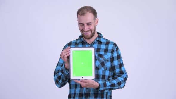 Happy Bearded Hipster Man Showing Digital Tablet and Looking Surprised
