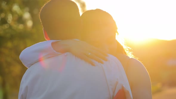 The Young Girl Put Her Head on the Guy's Shoulder at Sunset