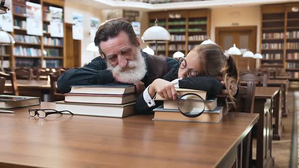 Tired Bearded Senior Man and His Teen Pretty Granddaughter Sleeping on Books in the Library