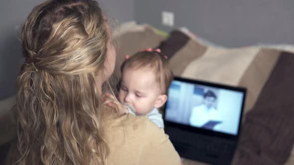 Telemedicine concept - young woman video chat with family doctor talking about her sick daughter.