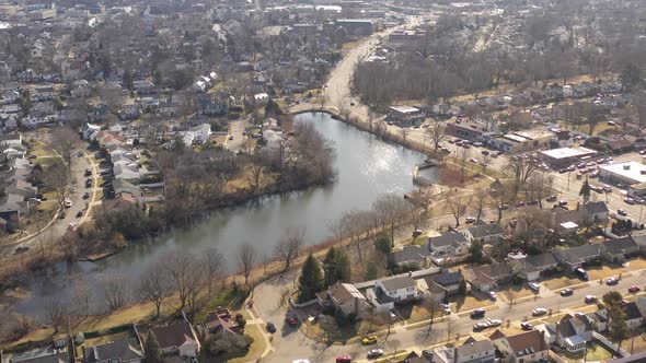 An aerial shot of a pond in a suburban neighborhood on Long Island, NY.  The camera dolly out, pan l