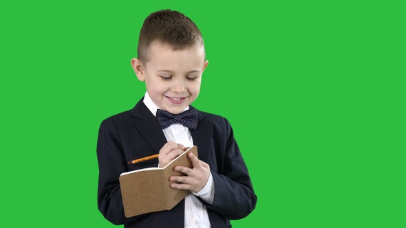 Boy in a formal clothes writing in check list or notebook