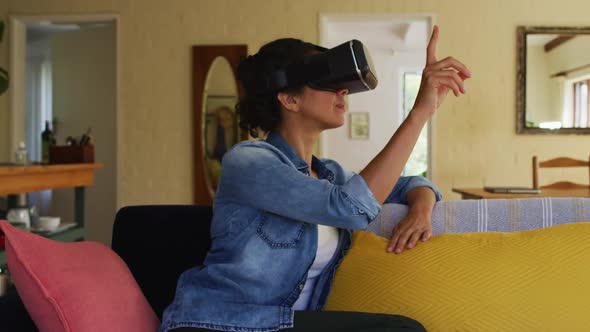 Caucasian woman wearing vr headset, sitting on sofa at home