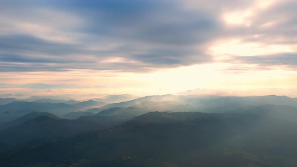 4K Flying through the clouds above mountain tops. Tropical forest with smoke and fog.