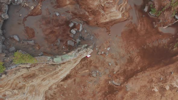 Aerial View of a Man Climbing Onto the Rock Within Unique Volcanic Landscape