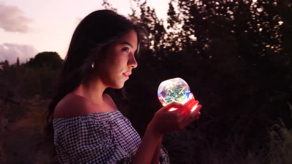 A beautiful woman sorcerer wandering in a fantasy landscape with a magic spiritual orb glowing in il