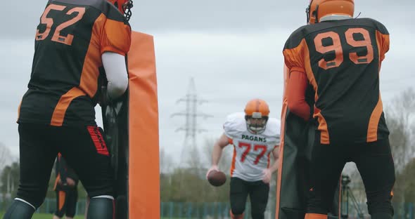 American Football Soccer Player in in Protective Gear Runs Through an Obstacle and Breaks Forward