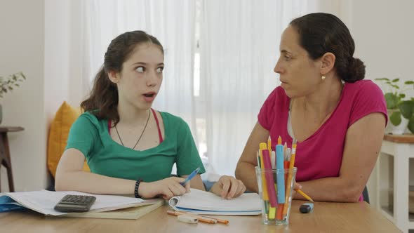 Mother helping her teenage daughter prepare homework