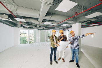 hardhats standing together inside new building planning further work, copy space