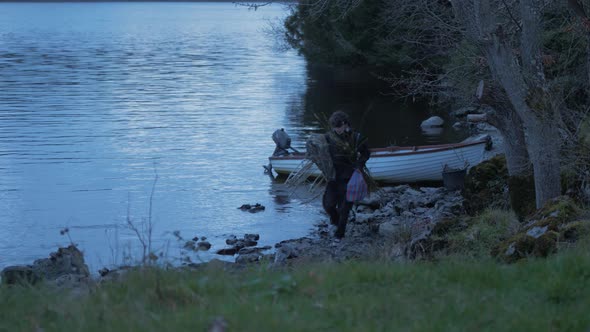 Young man carrying fish trap and supplies from lake boat