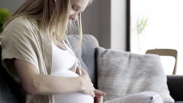 Tranquil Pregnant Woman Massaging Belly and Listening To Music