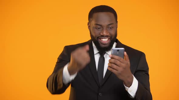 Happy Afro-American Businessman Holding Smartphone and Making Yes Gesture, Win