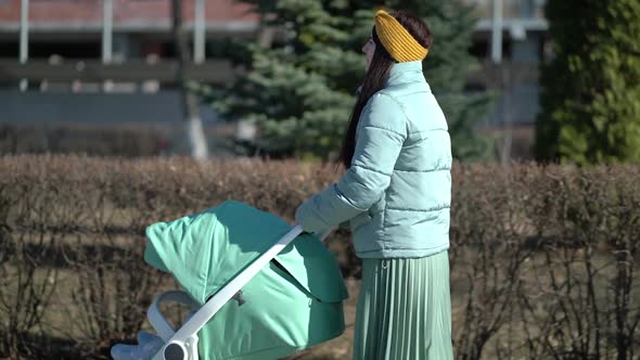 Woman Walking Through the Park with a Pram