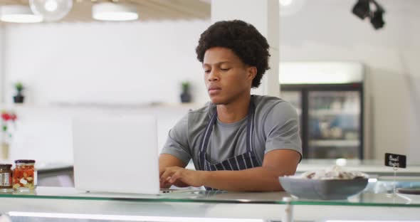 Animation of serious biracial waiter using laptop in coffee shop