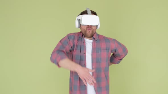 Man with Virtual Reality Glasses Dancing in the Studio on a Yellowgreen Background