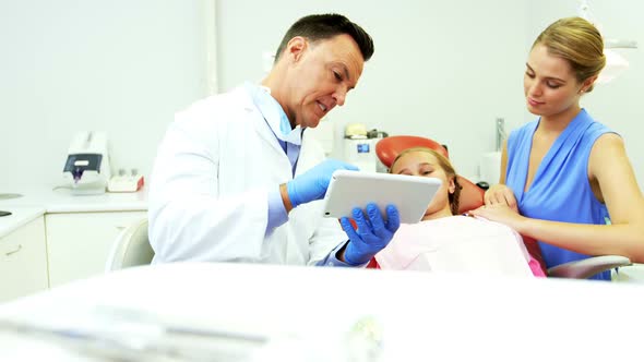 Dentist interacting with young patient over digital tablet