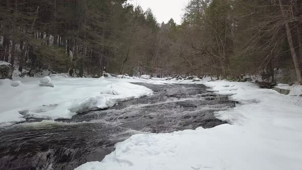 Drone flying low above snowy river rapids