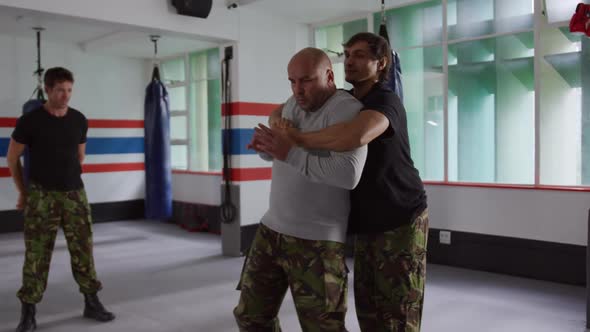 Caucasian man learning self defense from trainer in gym