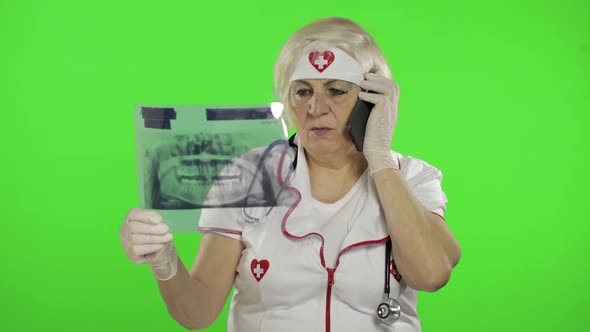 Elderly Female Doctor Talking on the Phone with Client. Dentist