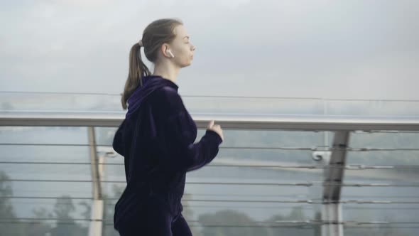 Side View of Confident Caucasian Runner Jogging on Misty Morning Outdoors