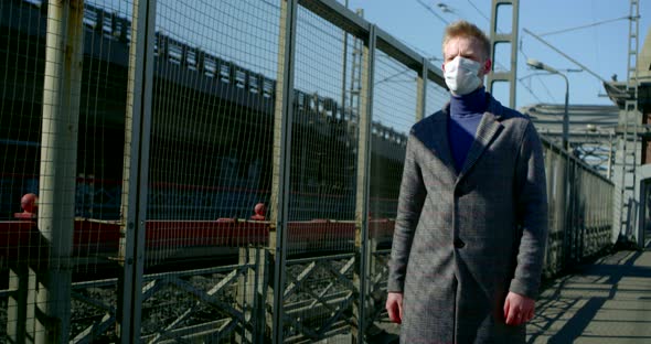 Portrait of a Man on a City Street. He Puts a Disposable Mask on His Face and Walks Along the Metal