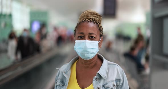 Mature african woman looking on camera while wearing safety face mask for coronavirus outbreak