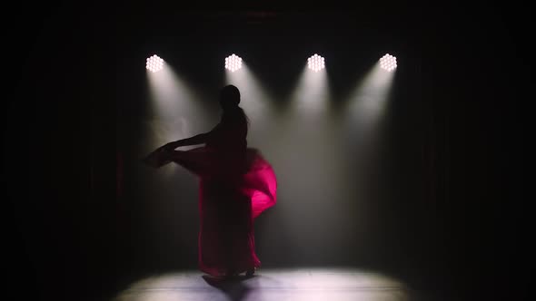 Silhouette a Young Girl Dancer in a Red Sari. Indian Folk Dance. Shot in a Dark Studio with Smoke