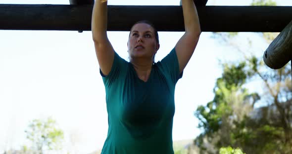 Determined woman exercising on monkey bar during obstacle course