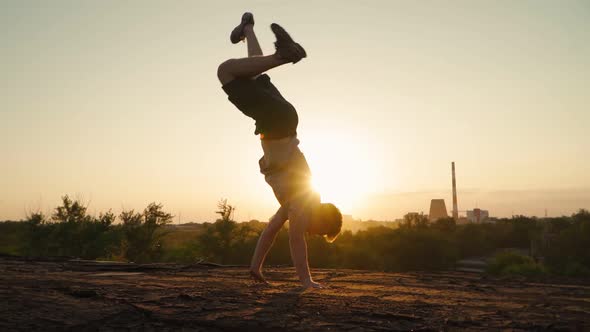 Stylish man dancing break dance against the backdrop of a beautiful sunset. Slow motion